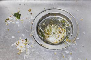 An image of a Kitchen Sink with Food Scraps | 5 Ways To Keep Your Kitchen Sink Sparkling